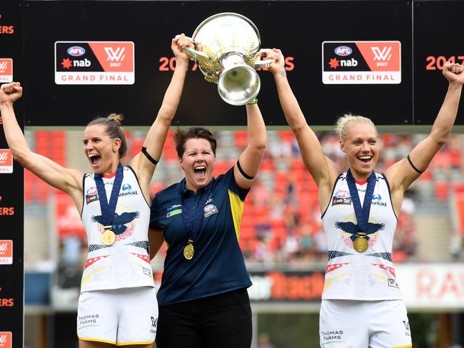 Co-captains Randall and Phillips hold aloft the 2017 AFLW premiership cup with their inaugural coach Bec Goddard. Picture: Dan Peded