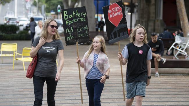 Protesters arrive at the rally outside Tony Abbott’s office carrying placards asking for Adani to be stopped and for a greater focus on batteries.