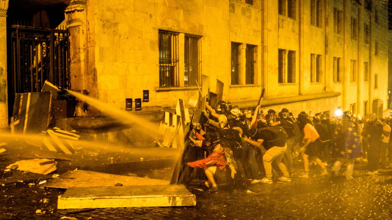 Protesters obstruct the Georgian Parliament building in Tbilisi while riot police attempt to disperse them with tear gas and water cannons. Clashes erupted over the Foreign Agent bill, which protesters believe signifies a shift towards authoritarianism. Picture: Nicolo Vincenzo Malvestuto/Getty Images