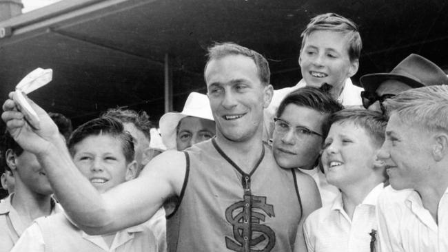 Sturt footballer 1961 Magarey Medallist John Halbert proudly shows some fans his medal before the '61 Grand Final match between West Adelaide and Norwood.