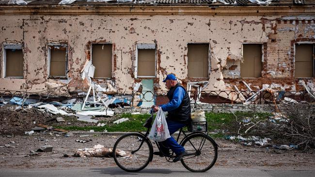 A man rides a bicycle past a destroyed house north of Kharkiv, in northeastern Ukraine. Picture: AFP