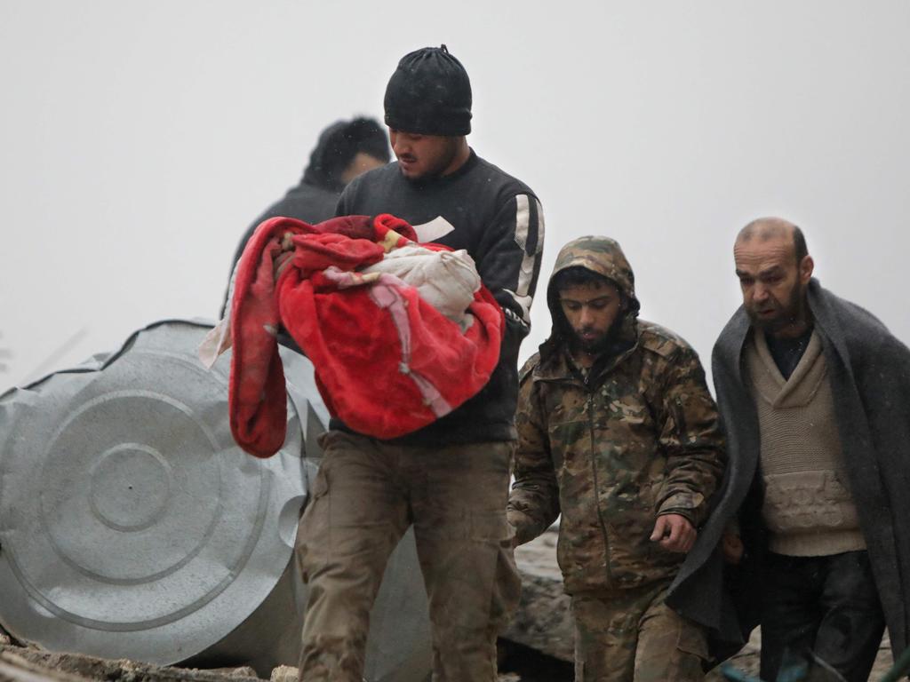 A Syrian man carries the body of an infant who was killed in an earthquake in the town of Jandaris, in the countryside of Syria's northwestern city of Afrin in the rebel-held part of Aleppo province. Picture: AFP