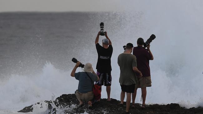 Photographers negotiate conditions at Snapper Rocks on the Gold Coast, Thursday February 21, 2019. Huge swells and high tides are set to pummelling southeast Queensland beaches over the coming days as Cyclone Oma tracks towards the Queensland coast. (AAP Image/Dave Hunt)