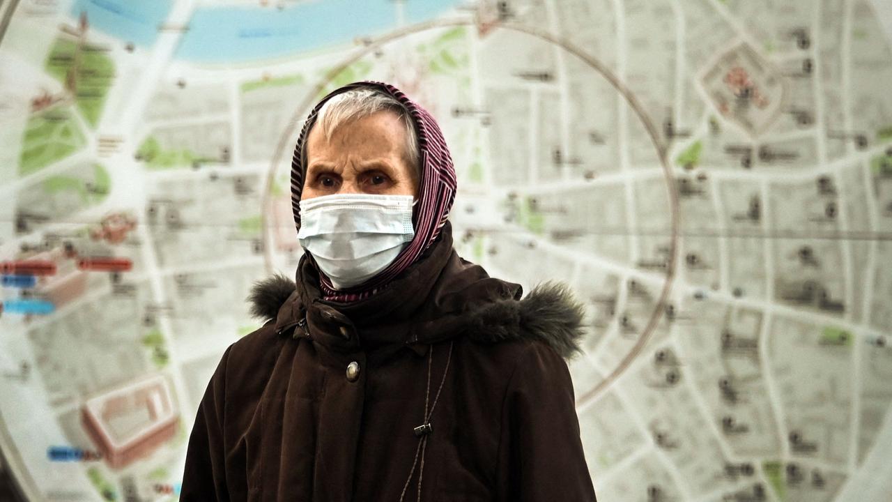 A woman wearing a protective mask walks past a street map in central Moscow as new restrictions are announced. (Photo by Alexander NEMENOV / AFP)