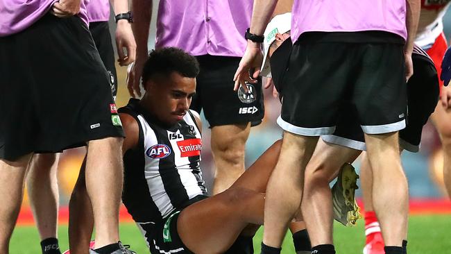 Isaac Quaynor of the Magpies is taken off the ground injured against the Swans with a horror gash to his leg. (Photo by Jono Searle/AFL Photos/via Getty Images)