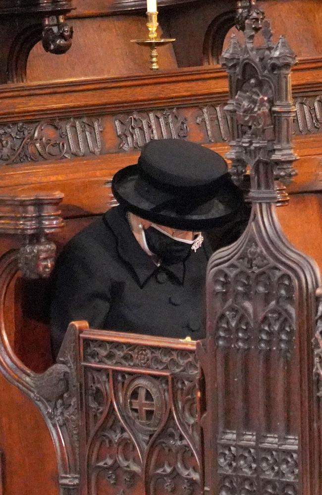 Coronavirus restrictions made the Queen a solitary figure in St George’s Chapel as she bowed her head (above) during Prince Philip’s funeral. Picture: Jonathan Brady/Getty Images