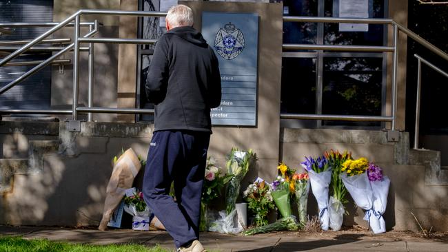 A man walks past floral tributes at Boroondara police station. Picture: Luis Ascui/Getty Images