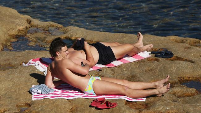 Two guys sun bake at Clovelly Beach in Sydney. The public has been asked to adhere to the strict social distancing guidelines put in place by the government to combat the spread of COVID-19 as well as only using the beach to exercise. Picture: Richard Dobson / News Corp