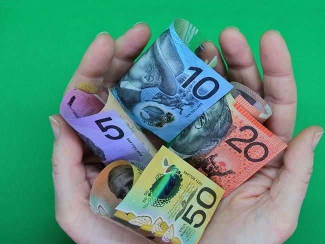 POV (point of view) of a person holding Australian dollar currency bank notes with his two hands isolated on a green background. ; share dividends generic