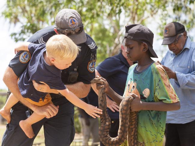 Sergeant Mark Carrington and his son Ben touching a snake Gapuwiyak boy Abraham Ganambarr caught. Picture: Floss Adams.