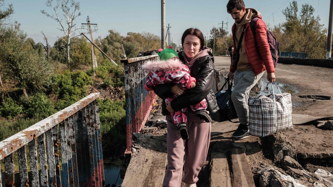 Viktoria Plotnykova, 20, holds her 9-month-old daughter Rita as they evacuate on the destroyed bridge over the Oskil River in Kupiansk, Kharkiv region, on September 29. Picture: by Yasuyoshi Chiba / AFP