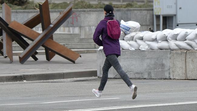 A woman runs past anti-tank structures blocking the streets during an air raid alert in the centre of Kyiv. Picture: AFP