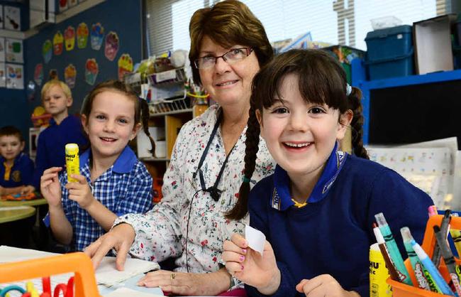 Amberley District State School teacher Christine New uses a Baha, or Bone Anchored Hearing Aid, to help her keep teaching her prep students, including Lily Goulding (left) and Matarna Ashworth. Picture: David Nielsen