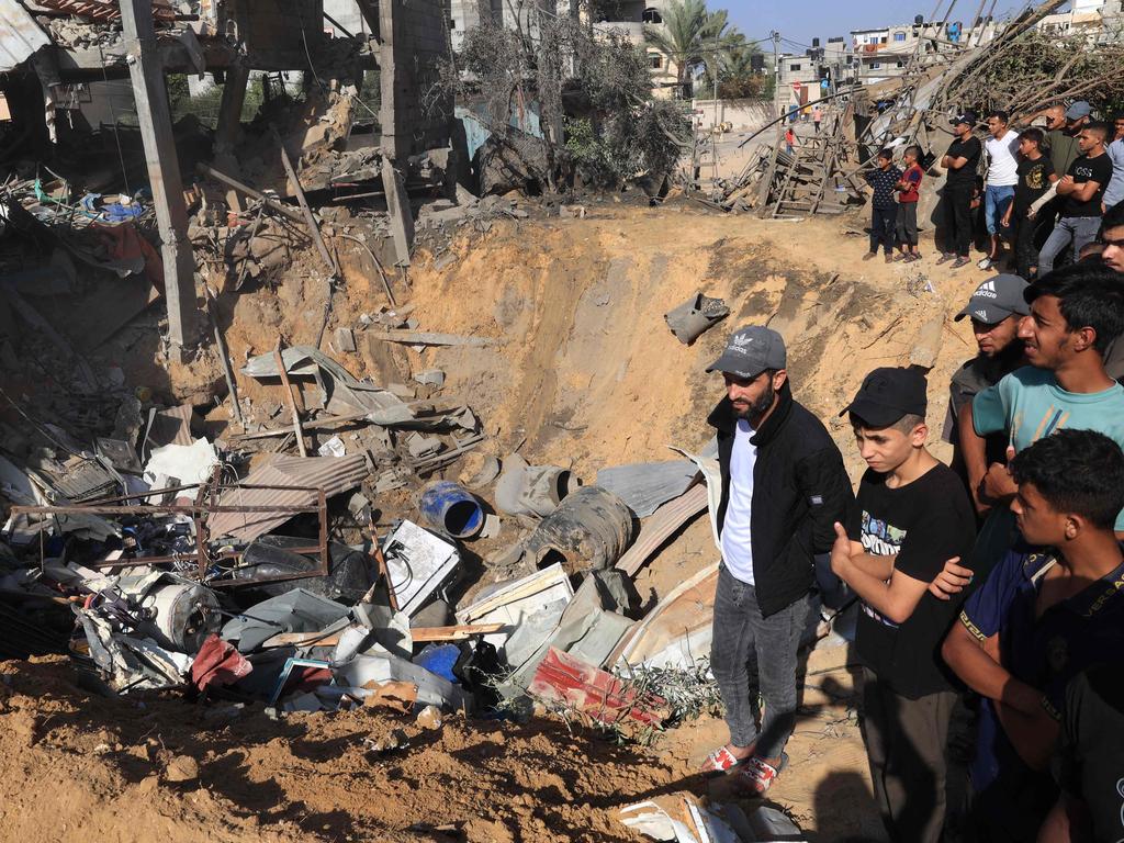 Palestinians stand on the edge of a crater following an Israeli strike on Rafah city, in the southern Gaza Strip on November 9, 2023. Picture: SAID KHATIB / AFP