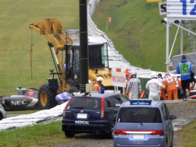 In this Sunday, Oct. 5, 2014 photo, rescuers and others gather around the car of Marussia Formula One driver Jules Bianchi after crashing during the Japanese Formula One Grand Prix at the Suzuka Circuit in Suzuka, central Japan. Bianchi was unconscious when he was taken to a nearby hospital following a crash during Sunday's rain-shortened race and is undergoing emergency surgery after a scan revealed a severe head injury. (AP Photo/The Asahi Shimbum) JAPAN OUT, NO SALES, MANDATORY CREDIT, ONLINE OUT