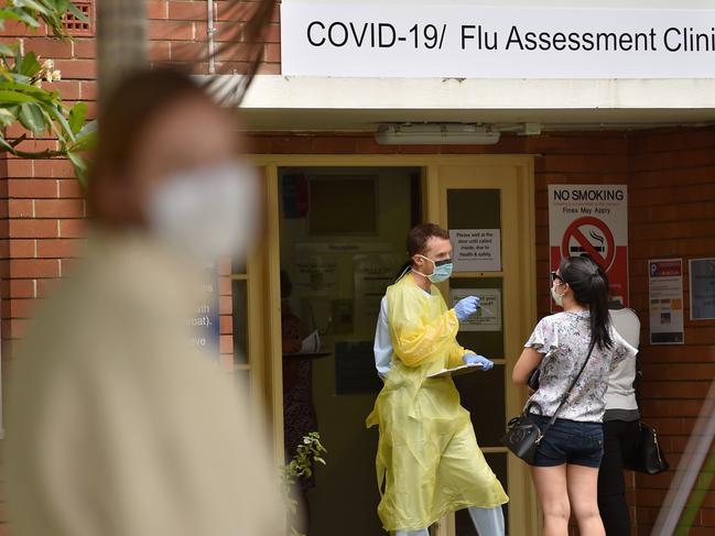 A health worker talks to visitors at a Covid-19 testing centre in Sydney on March 23, 2020. - With the imminent closure of pubs, restaurants, cafes and entertainment venues in Sydney, large queues formed outside Australian unemployment benefit offices as online services crashed as the prime minister warned the coronavirus pandemic would cause an economic crisis akin to the Great Depression. (Photo by PETER PARKS / AFP)