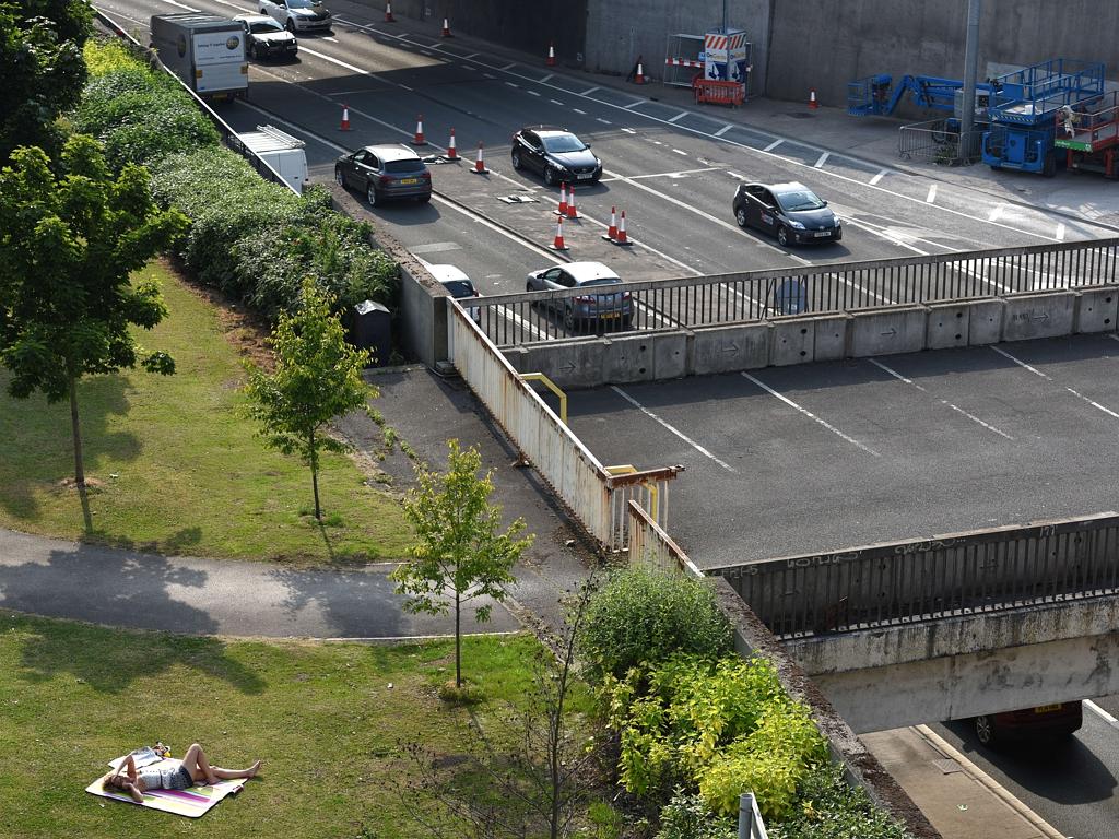 A woman sunbathes in warm weather next to a busy dual carriageway road in central Leeds, northern England on July 1, 2015. Picture: AFP