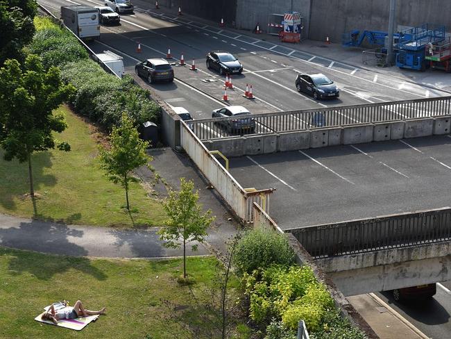 A woman sunbathes in warm weather next to a busy dual carriageway road in central Leeds, northern England on July 1, 2015. Picture: AFP