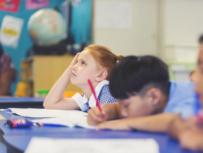 School children bored and tired in class. They are sitting are desks in a classroom in school uniforms. Some are falling asleep. Multi Ethnic Group