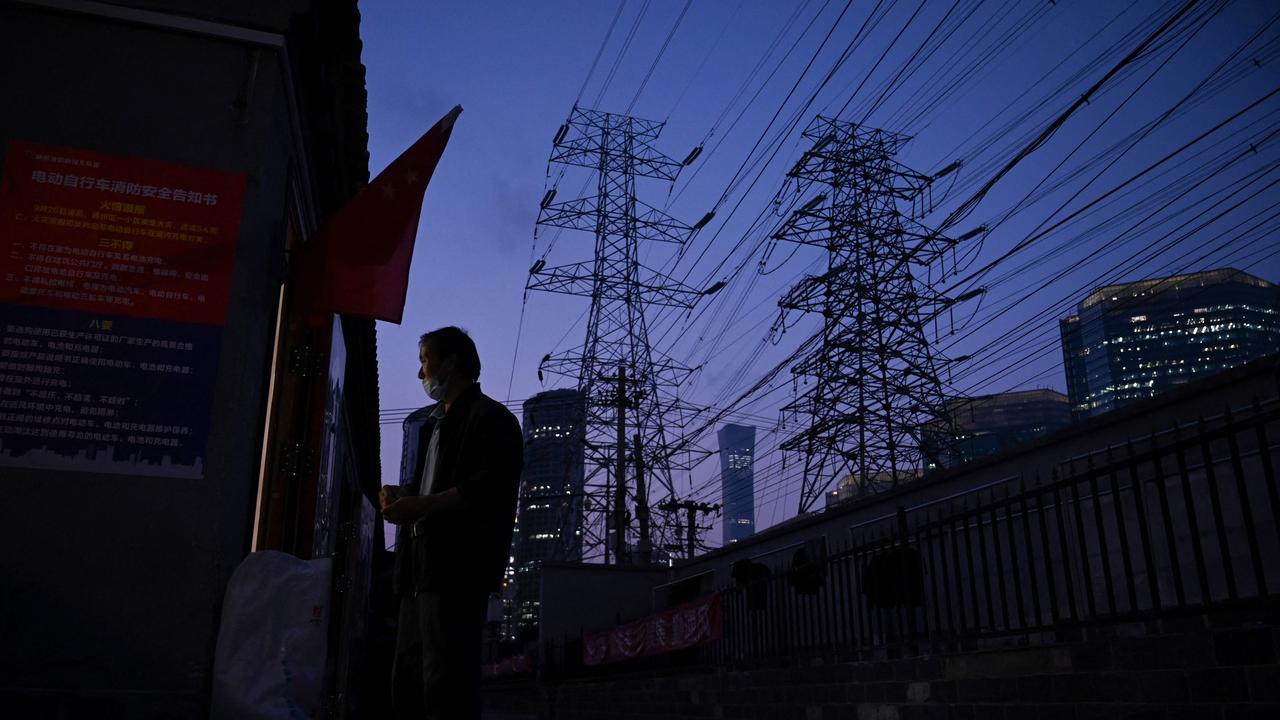 A man stands at a doorway below power lines in Beijing on September 28, 2021. Picture: AFP