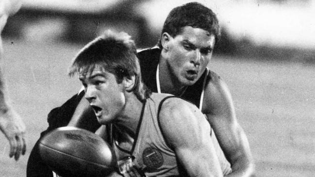 Sturt champion Peter Motley handballs under pressure from Martin Leslie in 1985.