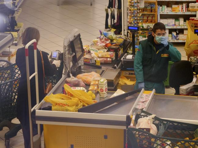 This photo shows a woman keeping the ‘safe’ from the supermarket cashier in Rome. Picture: AP Photo/Paolo Santalucia