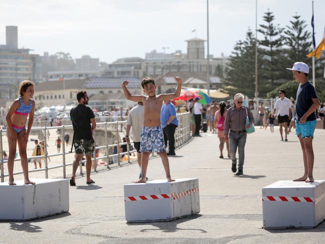 From left: Victoria DiBlasio, 9, with her brother Joseph, 7, and their cousin Riley Demos, 12, play on the security bollards installed at Bondi ahead of New Year’s Eve celebrations. Picture: Liam Driver