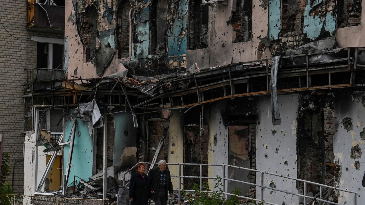 TOPSHOT - A couple walks between debris in the city of Izium, Kramatorsk, eastern Ukraine, on September 11, 2022, amid the Russian invasion of Ukraine. - Ukraine said on Sptember 11, 2022, that its forces were pushing back Russia's military from strategic holdouts in the east of the country after Moscow announced a retreat from Kyiv's sweeping counter-offensive. (Photo by Juan BARRETO / AFP)