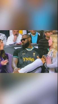 LeBron sits courtside next to team owner Jeanie Buss and Linda Rambis