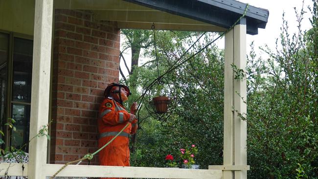 SES volunteer Keith Haycraft tries to secure a rope line to a roof at a house in Symons Ave, Boambee. Picture: Chris Knight