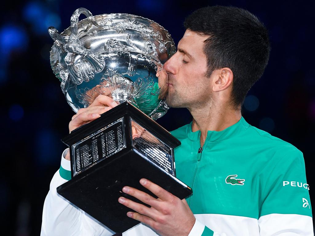(FILES) In this file photo taken on February 21, 2021, Serbia's Novak Djokovic kisses the Norman Brookes Challenge Cup trophy following his victory against Russia's Daniil Medvedev in their men's singles final match on day fourteen of the Australian Open tennis tournament in Melbourne. - Detained tennis world number one Novak Djokovic fought against deportation from Australia on January 6, 2022, after the government revoked his visa for failing to meet pandemic vaccine entry requirements. (Photo by William WEST / AFP) / -- IMAGE RESTRICTED TO EDITORIAL USE - STRICTLY NO COMMERCIAL USE --