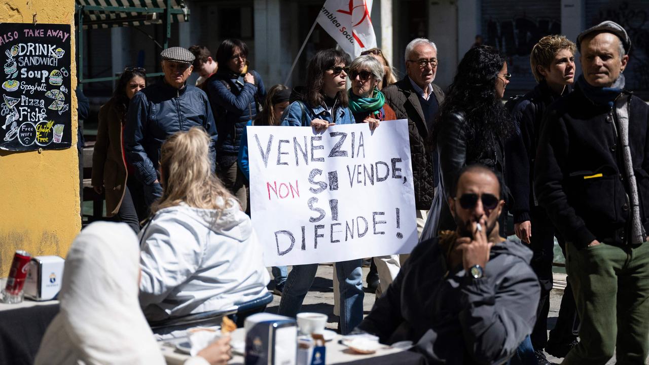 A woman holds a banner reading ‘Venice is not sold, it is defended’ as protesters took part in a demonstration, against the new ‘Venice Access Fee’. Picture: Marco Bertorello / AFP