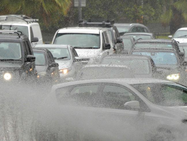 A car drives through water, caused by heavy rain, on a road in Sydney on November 28, 2018. - Flights were cancelled, railway lines closed and motorists stranded on flooded roads as a month's worth of rain fell on Sydney early on November 28, leaving emergency services battling to respond. (Photo by Peter PARKS / AFP)