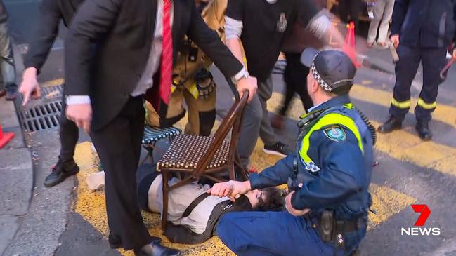 Bystanders subdue Ney with chairs while a policeman calls for backup. Picture: Seven News