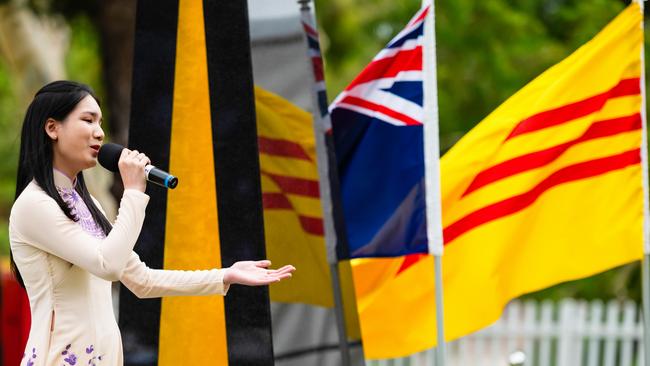 . Dorothy Nguyen sings “Thank You Australia” song at the Unveiling Ceremony of the Vietnamese Boat People Monument in front of Australian and Co Vang flags. Picture: OFFGRIDPHOTOGRAPHY.COM.AU