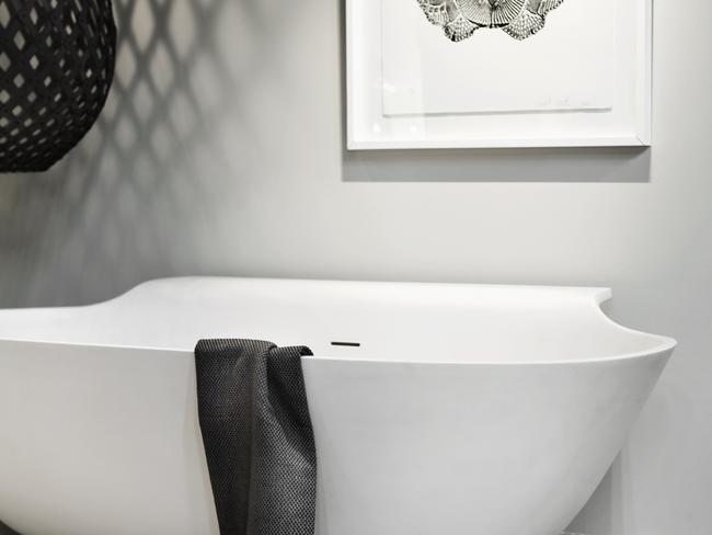 A white bathtub is set off by darker accessories in this Rogerseller bathroom.