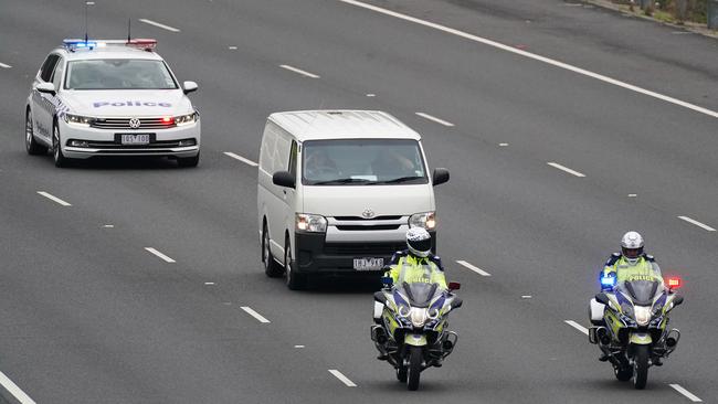 A police escort is given to a coroners van transporting bodies from the scene of a collision near the Chandler Highway in Kew in Melbourne.