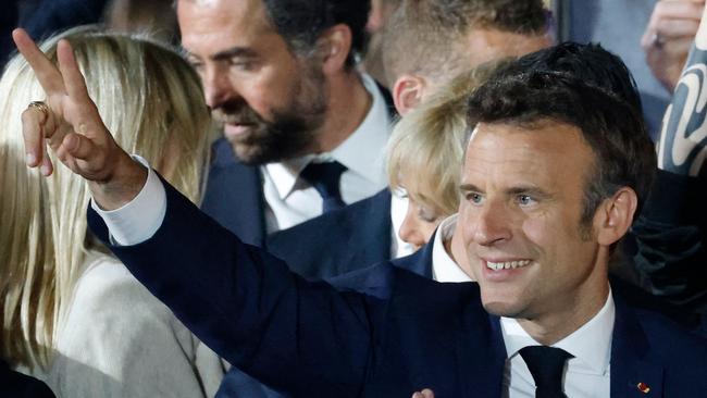 French President Emmanuel Macron flashes the V-sign as he greets supporters after his victory in France's presidential election, at the Champ de Mars in Paris.