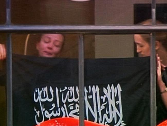 Hostages Marcia Mikhael and Katrina Dawson were both forced to hold up a flag supporting Islamic State.