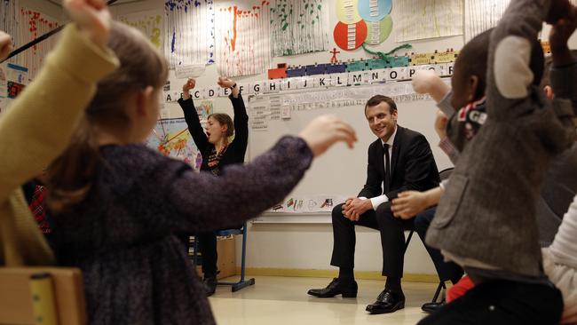 French President Emmanuel Macron listens to pre-school children as he visits the Emelie pre-school in Paris.