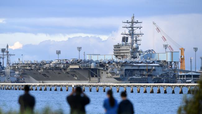 Locals look at the aircraft carrier USS Ronald Reagan docked at the Port of Brisbane in 2019.