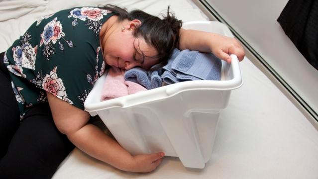 Latina woman has fallen asleep in a basket with several colorful folded towels