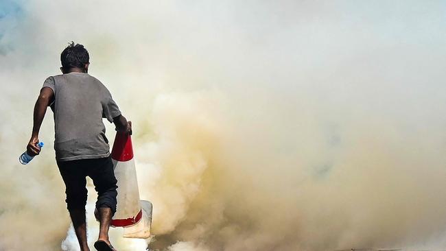 A demonstrators tries to douse a tear gas canister fired by police to disperse students protesting to demanding the resignation of Sri Lanka's President Gotabaya Rajapaksa over the country's crippling economic crisis. Picture: AFP