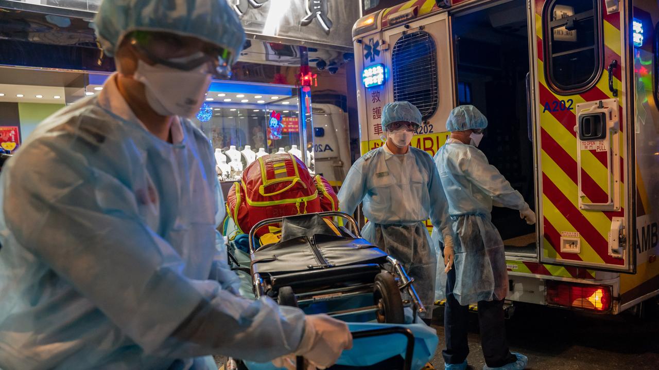 Paramedics wearing personal protective equipment carry a stretcher off an ambulance at North Point district in Hong Kong, China. Picture: Anthony Kwan/Getty Images