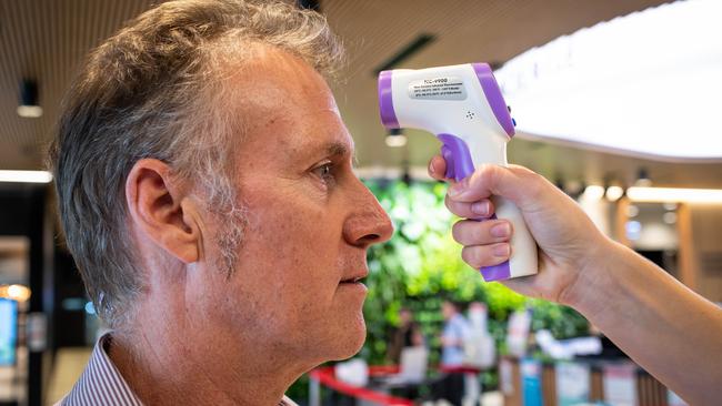 Registered Nurse Grace Heidke (24) from Cromer taking the temperatures of everyone arriving at Northern Beaches Hospital in Frenchs Forest on 23rd April 2020. Having his temperature taken is concierge Andrew Lang (55) from Dee Why. Picture: Julian Andrews.