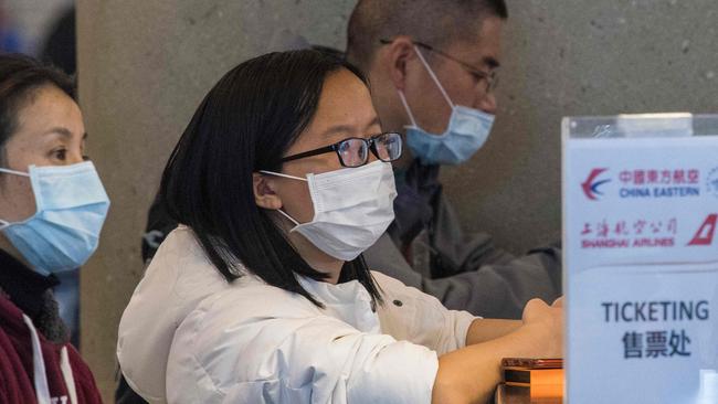 Passengers wear face masks to protect against the spread of the coronavirus as they wait for standby tickets on a China Eastern flight to Shanghai, at Los Angeles International Airport. Photo: Mark Ralston, AFP.