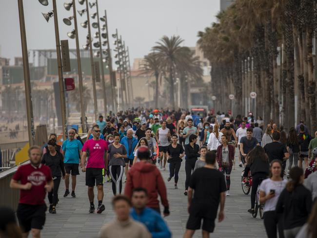 People walk and run along a promenade next to a reopened beach in Barcelona. Picture: AP.