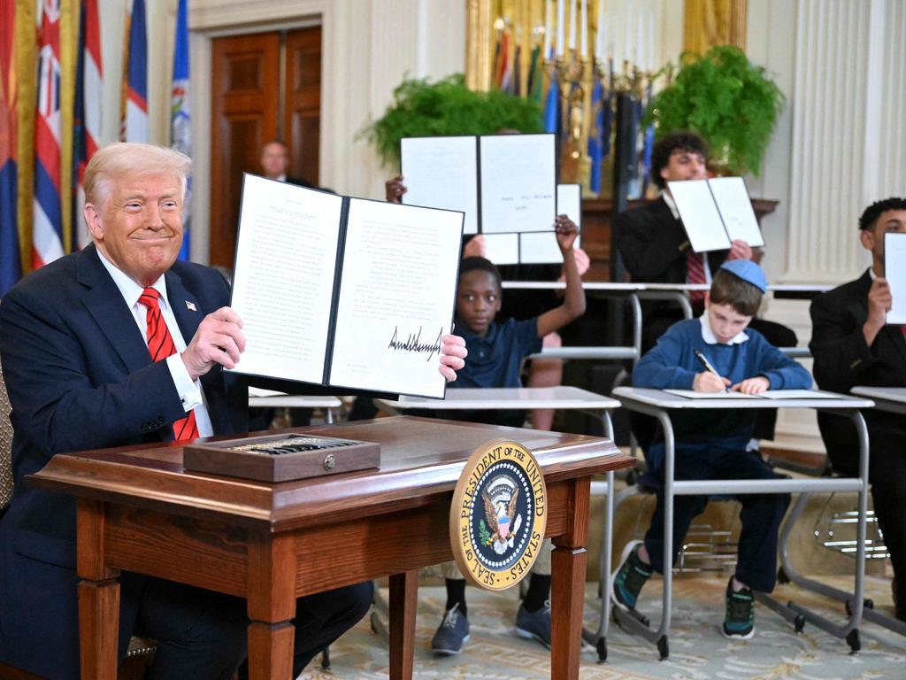 Donald Trump holds an executive order after signing it in the East Room of the White House in Washington, surrounded by schoolchildren. Picture: AFP