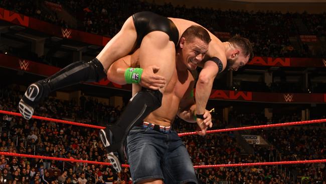 Cena taking down an opponent in the WWE ring.