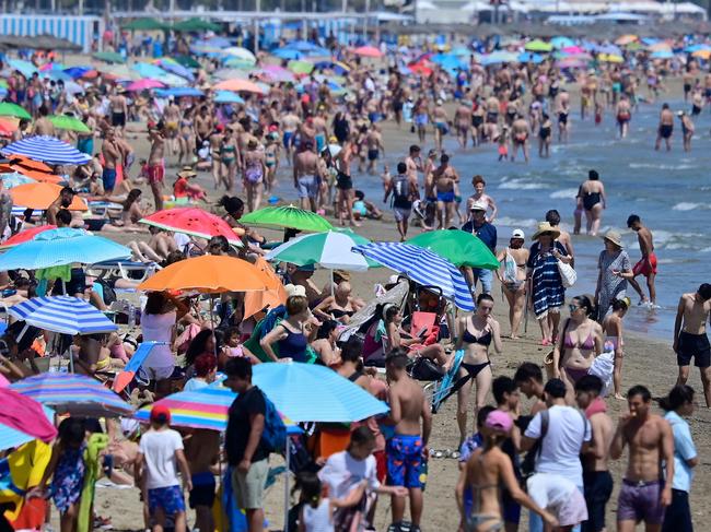 (FILES) People crowd the beach in Valencia on July 5, 2024. A record 94 million foreign tourists craving for sun, sand and culture flocked to Spain in 2024 as the sector drives the country's bullish economy, the tourism minister said on January 15, 2025. "In 2024, the forecast for international tourists is around 94 million, 10 percent more than 2023. Spain therefore continues to break records," Industry and Tourism Minister Jordi Hereu said in Madrid. (Photo by Jose Jordan / AFP)